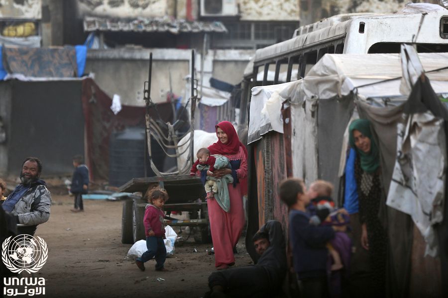 A mother holds her baby among the tents where displaced families live in Deir el-Balah